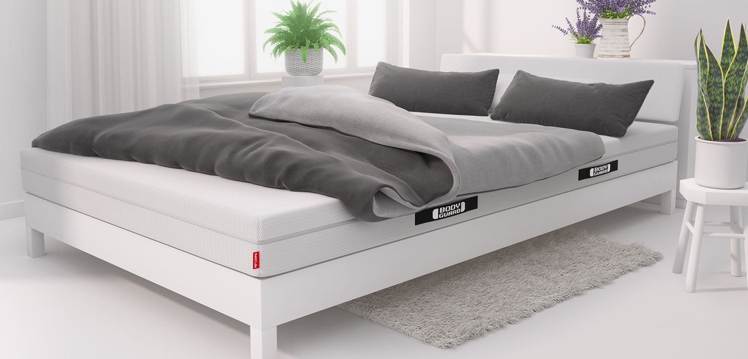 In a brightly lit bedroom stands a double bed with a 140x220 cm mattress, a double duvet and two pillows on top