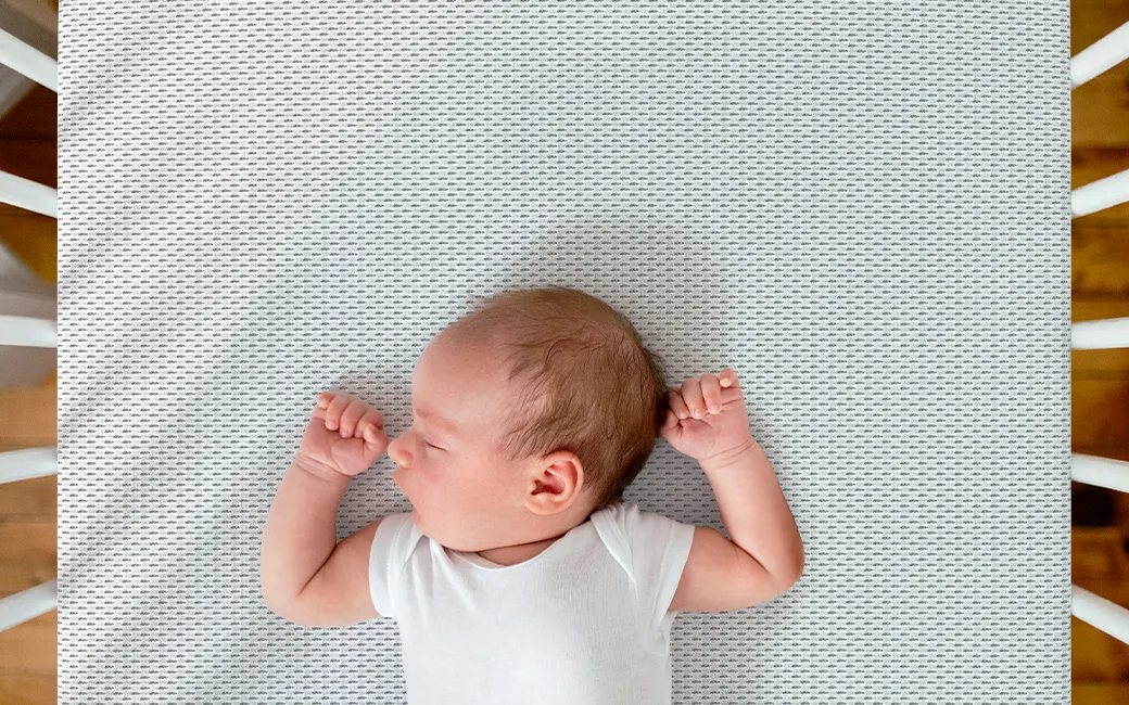 A newborn lays backwards on the SuperBreeze Kids Mattress.