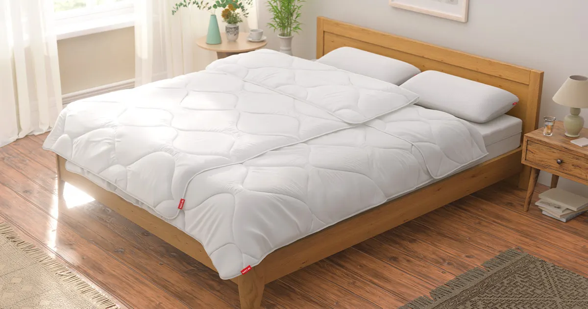 A bright, modern bedroom with a double bed. Two BODYGUARD Duvets 155x220 cm and two pillows are neatly arranged on the bed.