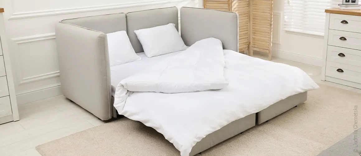 Photo: A 160x200 topper lies on a pull-out couch, with bedding for two people on top.