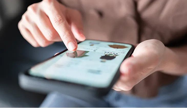 Eine Person mit Smartphone in der Hand. Ein Finger berührt den Bildschirm.