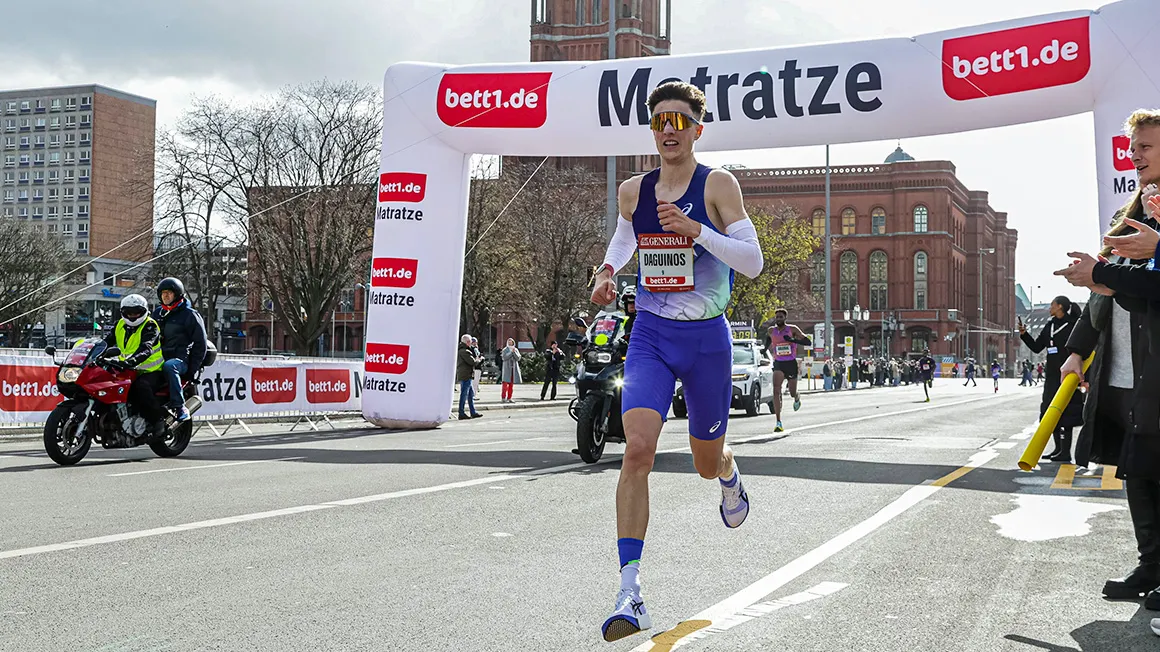 Eine Person durchquert einen bett1.de Torbogen auf der Strecke des Berliner Generali Halbmarathon am Roten Rathaus.