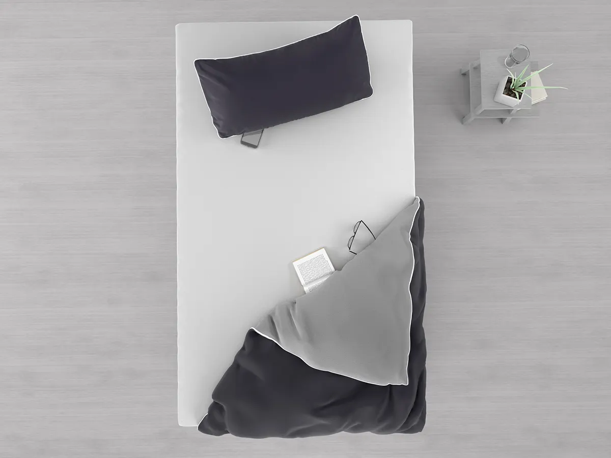 A bird's eye view of the 120x200 mattress. A pillow and a comforter lie on it.
