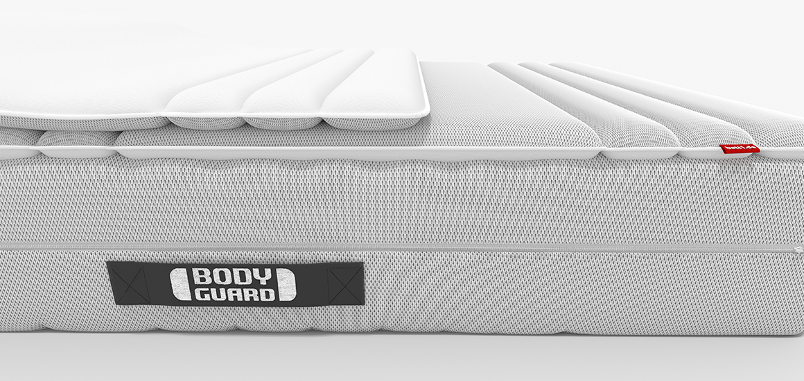 A BODYGUARD mattress partially covered with the BODYGUARD Topper. One half of the topper is folded back to reveal the reverse side of the cover.