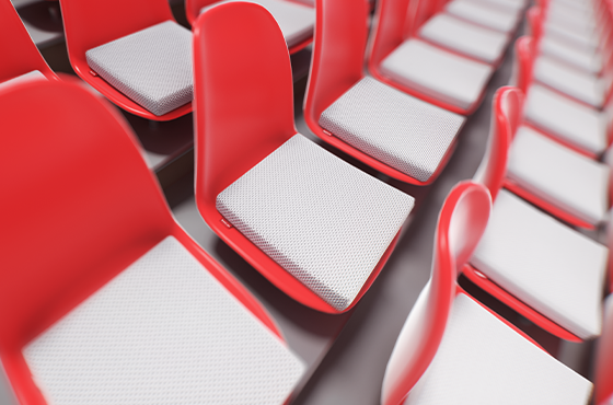 Red stadium seats are lined up next to each other. The BODYGUARD® seat cushion lies on the seats. 