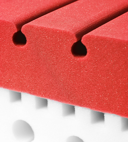 Section of the two-coloured BODYGUARD® mattress core: red at the top, white at the bottom.