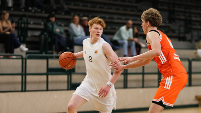Photo: A Berlin Braves player holds a basketball between his raised arms. 