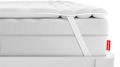 The BODYGUARD Topper lies on the BODYGUARD Mattress. Zoom on the attachment through the retaining strap	