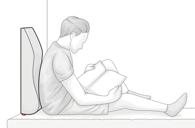 Illustration: A person is sitting in bed leaning against the vein cushion and reading a book.	