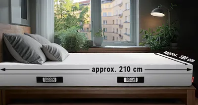 An 80x210 mattress lies in a bed. The dimensions are shown on either side