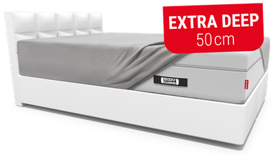 The BODYGUARD box spring mattress lies on a box spring bed and is covered with the extra high fitted sheet 200x200 cm. Button with text: Bridge height 28 cm.