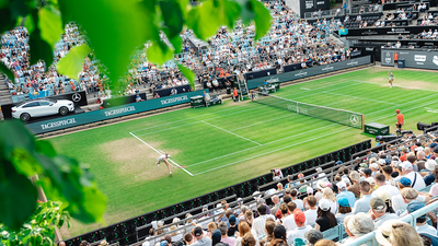 A view from the top tier of the stands, looking down over the packed stands towards the grass court.