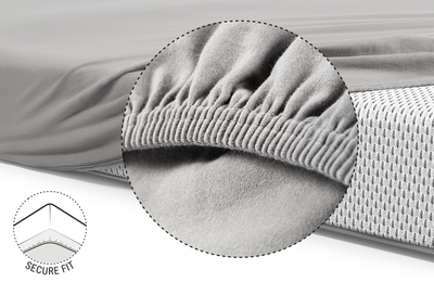  Half of the BODYGUARD® mattress is covered with the children's fitted sheet in silver. Zoom on the reinforced and elasticated hem. Illustration showing the underside of the mattress over which the hem of the sheet is pulled. Text: secure hold	