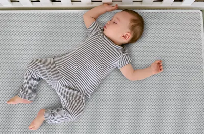 Ein Baby liegt auf dem Rücken in einem Babybett.
