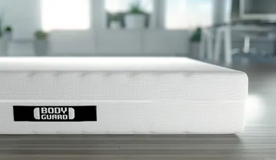 Die BODYGUARD Matratze liegt auf einem Holzboden.
