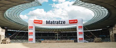In the middle of the Olympic Stadium in Berlin stands a large inflatable arch bearing the inscription: bett.de Mattress.